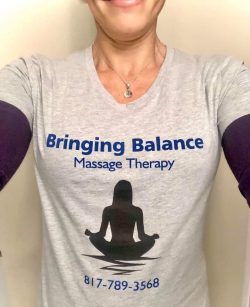 Person wearing a light grey T-shirt with "Bringing Balance Massage Therapy" and a silhouette of a person meditating, along with a phone number "817-789-3568".